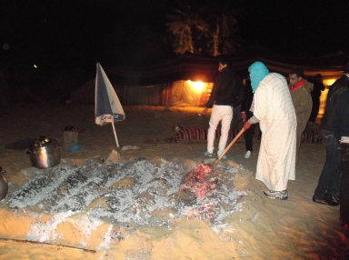 Roasting our food beneath the sand with hot coals, periodically refreshed. Taghit.